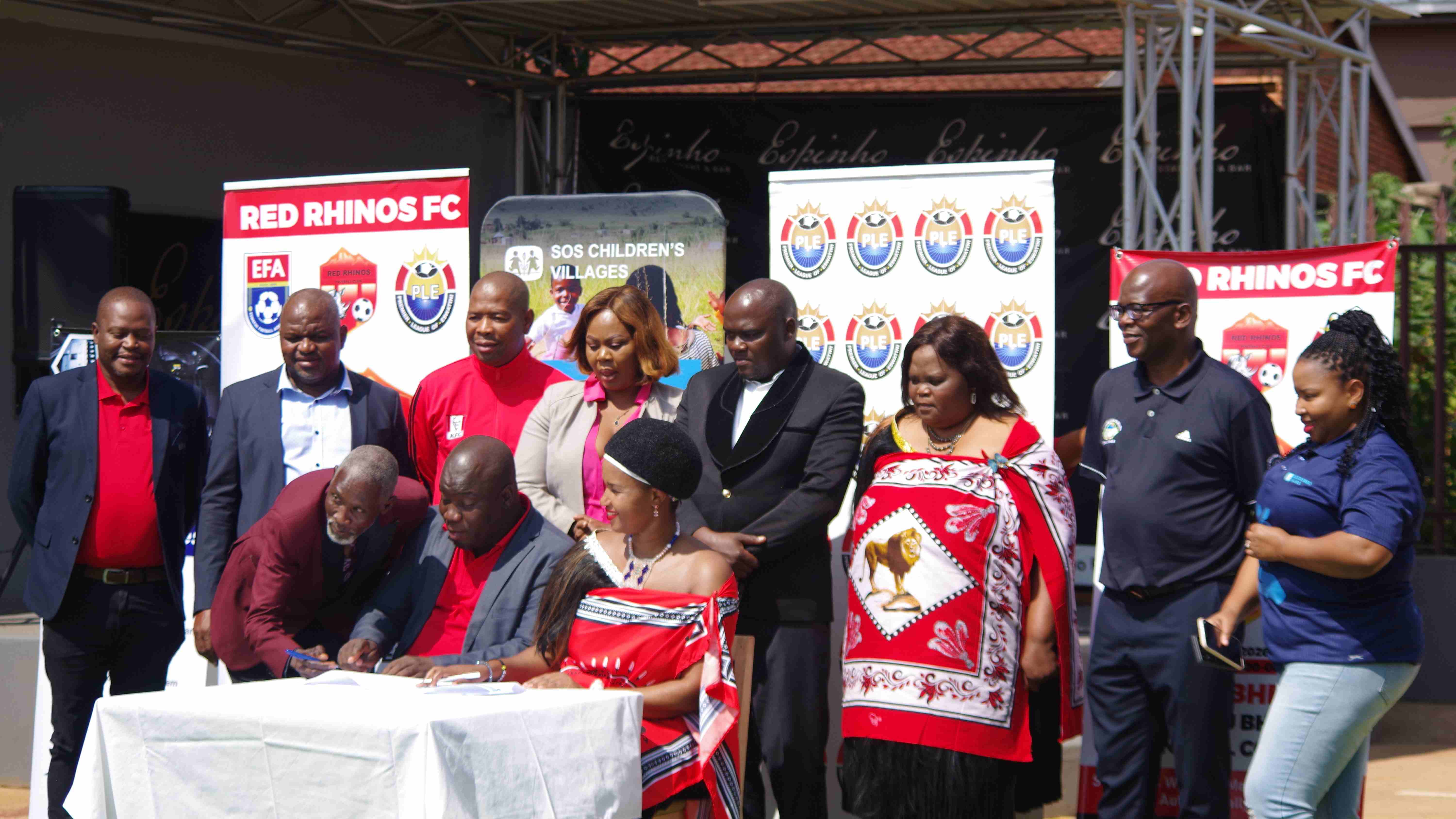 Red Rhinos Management Themba Mavimbela, President Sithembiso ‘Ngudze’ Mamba and SOS Children’s Village’s Bonsile Bhembe signing the MoU while other representatives of football stakeholders, including Dvokodvweni MP Sifiso Shabalala (back 2nd L), look on. 